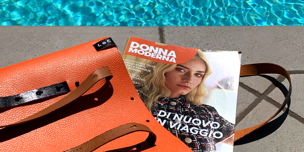 articolo donna moderna rivista estate 2020 che si intravede uscire dalla borsa camaleonte trasformabile e reversibile arancio nero da costruire a bordo piscina